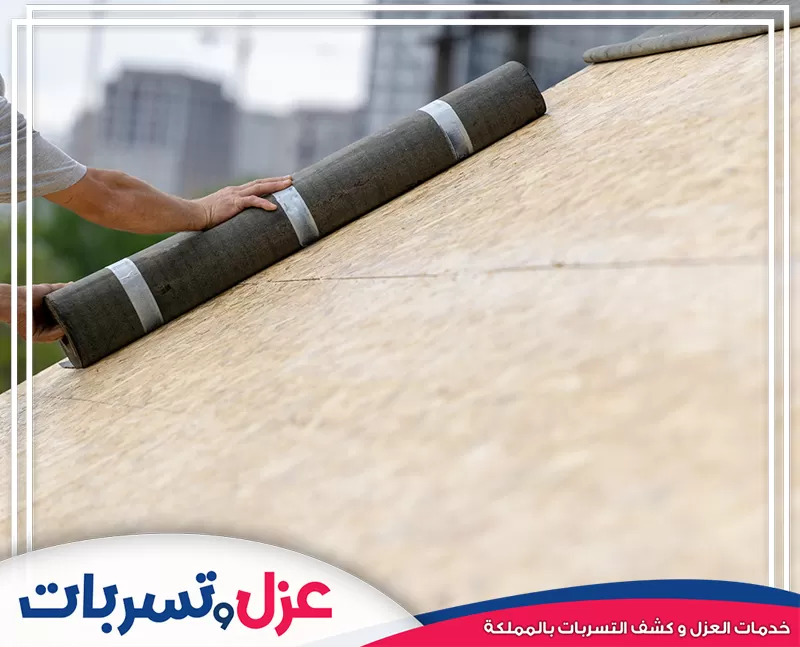 فني يركب رولات العزل المائي على سقف خشبي مائل، إحدى خدمات شركة عزل اسطح بنجران لحماية مثالية ضد التسرب.