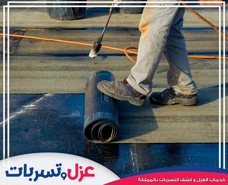 فني يركب رولات العزل المائي بالحرارة على السطح، لدى شركة عزل اسطح بالمدينة لضمان عزل مائي فعال.